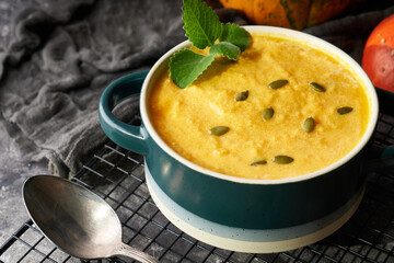 Traditional pumpkin soup puree with seeds in a bowl, on a dark background
