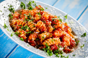 Fusilli with tomato sauce, meat and parmesan on wooden table
