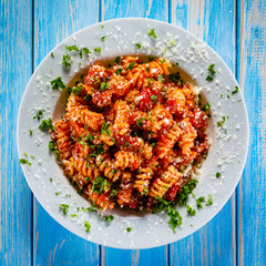 Fusilli with tomato sauce, meat and parmesan on wooden table
