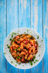 Fusilli with tomato sauce, meat and parmesan on wooden table
