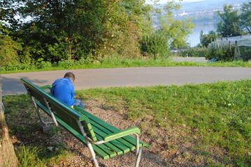 Kind im blaue pulover auf dem grünen bank
