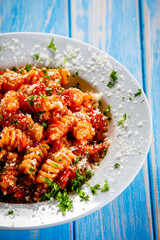 Fusilli with tomato sauce, meat and parmesan on wooden table
