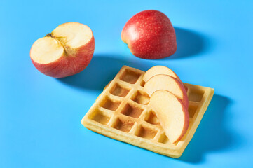 Vanilla belgian waffles with apple on blue background