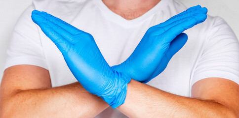 Fototapeta premium Male Doctor Hands Crossed make Stop Sign. Man in White T-shirt Wearing and Gloves Isolated on white background