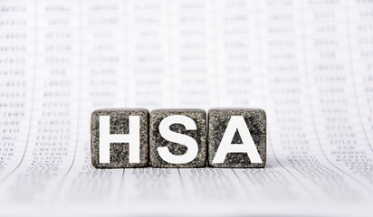 three stone cubes on the background of white financial statements, tables with the word HSA Health savings account. Strong business concept