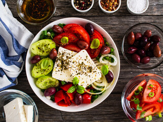Fresh Greek salad - feta cheese, tomatoes, cucumber, red pepper, black olives and onion on wooden table
