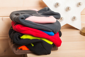Colorful fleece jackets lay stacked in a wooden room