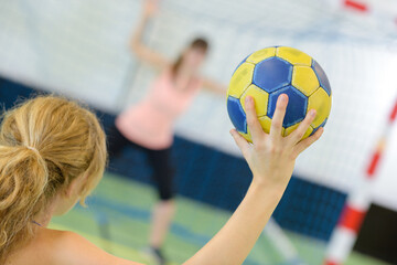 sportswoman holding a ball against handball field indoor