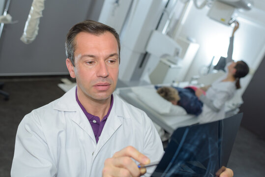doctor looking at xray patient under machine in background