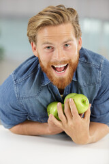man trying not to drop apples held against himself