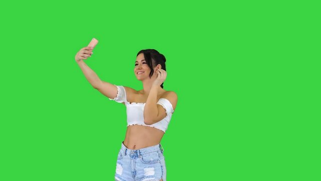 Beautiful young woman doing selfie on a Green Screen, Chroma Key.