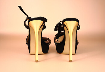 Sandals with gold high heels on a pink background