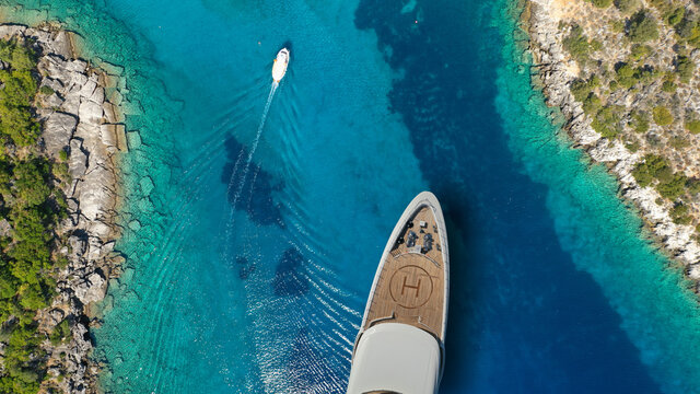 Aerial drone top view ultra wide photo of large yacht - boat with helicopter landing area anchored in tropical exotic paradise bay with turquoise open sea