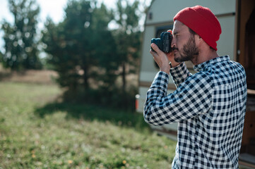 Man with a photo camera taking a picture in nature near the trailer at home.