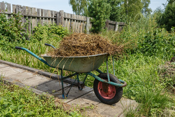 garden cart with natural cow dung. The cart is on a wooden bridge near the fence.