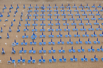 Rows of blue and white parasols and sunbeds on the beach. Italy.