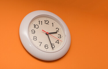 White clock with orange wall background.