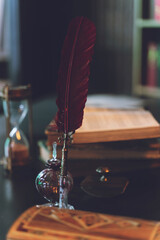 Old quill pen, books and vintage inkwell on wooden desk in the old office against the background of...