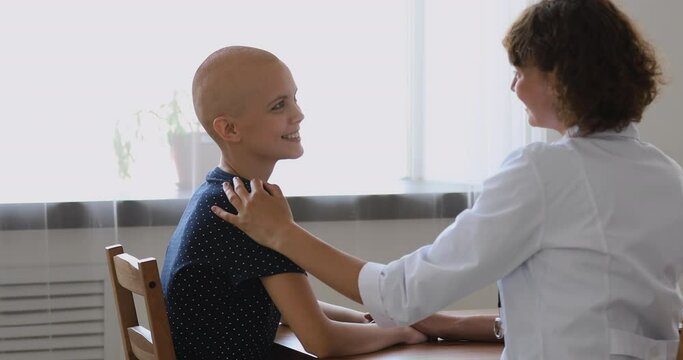 Concept of cancer patient rehabilitation, provide sympathy and professional psychological support give hope to ill person. Friendly oncologist doctor touch shoulder of bald 20s girl at medicare visit