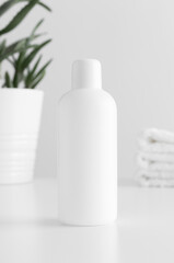 White cosmetic bottle mockup with a aloe vera and towels on a white table.