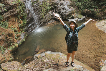 Woman tourist traveling adventure through the forest Successfully arrived at the destination.wearing travel gear hat and camera.outdoor freedom lifestyle.