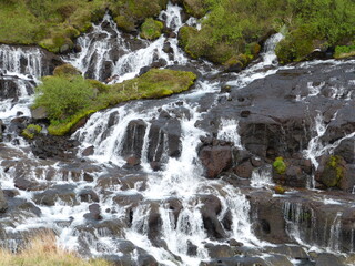 Waterfall Hraunfossar in Iceland. Stunning white uncountable falls run in cascade series down lava cliff. Hraunfossar Waterfalls runs down into Hvita River in Borgarfjordur. Natural beauty.