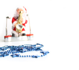 Gift blue garland. Defocused Toy santa claus playing saxophone on a white background. christmas post