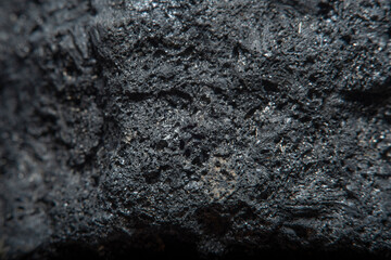 Blurred black background in soft focus with hard coal at high magnification. An image on the theme of geology and the extraction of minerals and natural fuels.