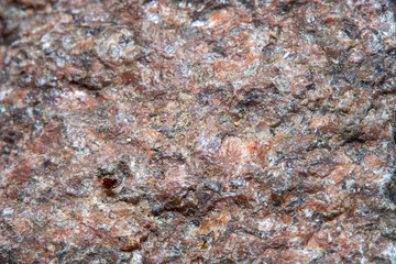Photograph of a granite surface in soft focus at high magnification. Fine texture of natural mineral of pink color with blurred background. Stone with soft stains of color.