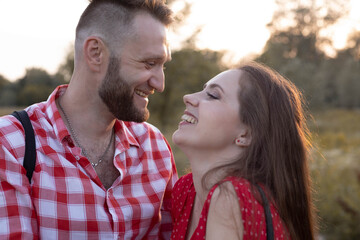 Beautiful guy with a girl walking in the field, a woman in a red dress, a brunette with long hair, a guy in a plaid shirt, love, relationships, couple, husband and wife