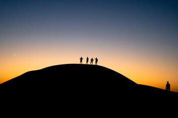 silhouette of a person on a mountain top climbing in desert