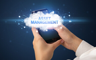 Female hand touching smartphone with ASSET MANAGEMENT inscription, cloud business concept