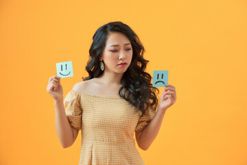 Photo of gloomy lady holding paper emoticons good and bad mood prefer negative emotions awful day