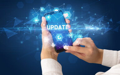 Female hand holding smartphone with UPDATE inscription, modern technology concept