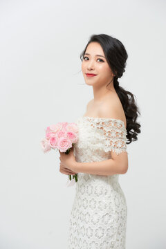 Young beautiful woman in a white dress posing with a bouquet of roses