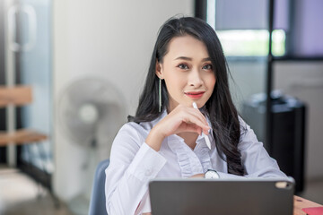 Successful young asian business woman working at the office. Looking at camera.