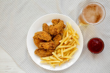 Homemade Crispy Chicken Wings and French Fries with glass of cold beer, overhead view. Top view, from above, flat lay. Space for text.
