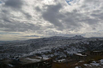 View from the top of settlements in Cappadocia. Misty view of the snowy hills of Cappadocia, Turkey.