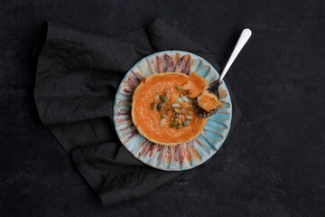 autumn orange creamy pumpkin pie for halloween with seeds on a ceramic plate on a towel on a black background, place for text