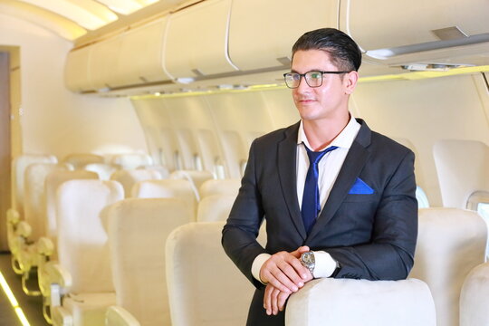 Handsome Caucasian businessman in formalwear inside the airplane with passenger seat on the background with copy space