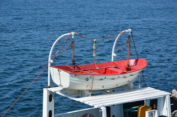 Emergency aid boat in the dock of the ship. Blue sea in the background.