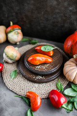 Unusual tomatoes on wooden stands on a dark table. Still life with autumn bright vegetables.
