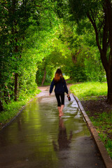 A girl walks barefoot along an alley in the pouring rain. - 378933587