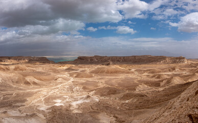 Panoramic landscape of the remote part of the Judean Desert, Israel. Hills, natural terraces with escarpments and dry wadies of the Judean Desert. Dead sea on the background.