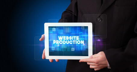 Young business person working on tablet and shows the inscription: WEBSITE PRODUCTION