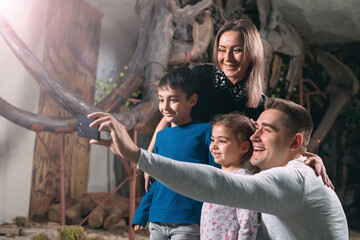 A family takes a selfie against a mammoth skeleton at the Museum of paleontology.