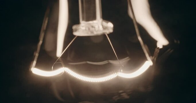 Closeup Shot Of The Wire Filament Of A Classic Incandescent Light Bulb Gradually Turning On And Off.