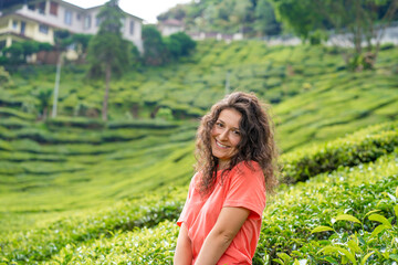 Beautiful brunette girl posing in the middle of the tea valley between green tea bushes.