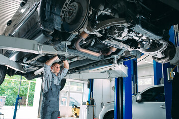 Portrait of a mechanic repairing a lifted car.