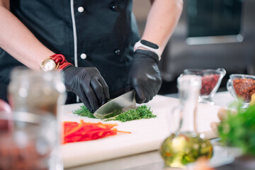 A Woman Chef cuts vegetables in the kitchen in a restaurant.